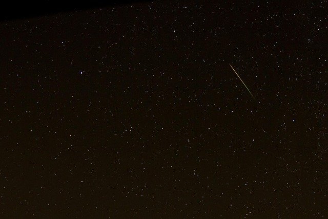 Meteoro šviesos takas žvaigždėtame nakties danguje
